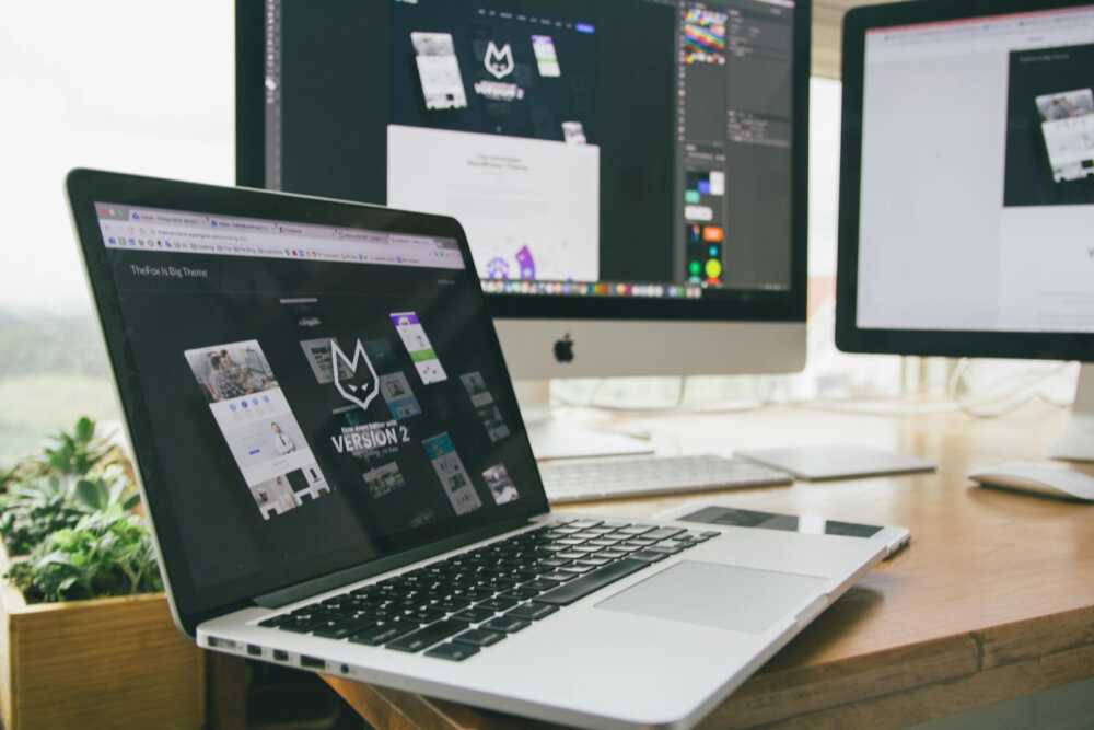 A stylish workspace featuring a laptop and monitors displaying design software.