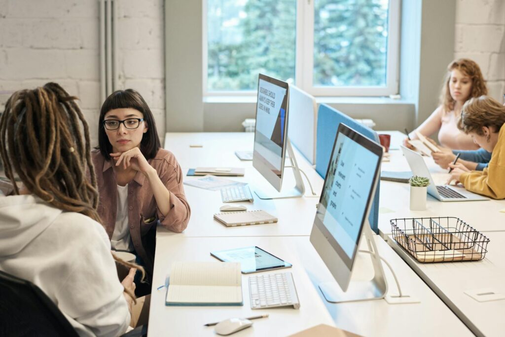 Diverse group of women working together in a modern office setting, fostering teamwork and creativity.