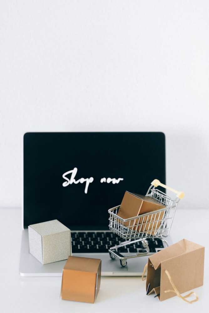 Minimalist online shopping setup with laptop, cart, and packages symbolizing e-commerce.